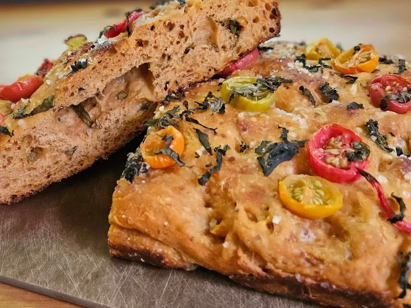 Artisan focaccia with fresh herbs, cherry tomatoes, and peppers