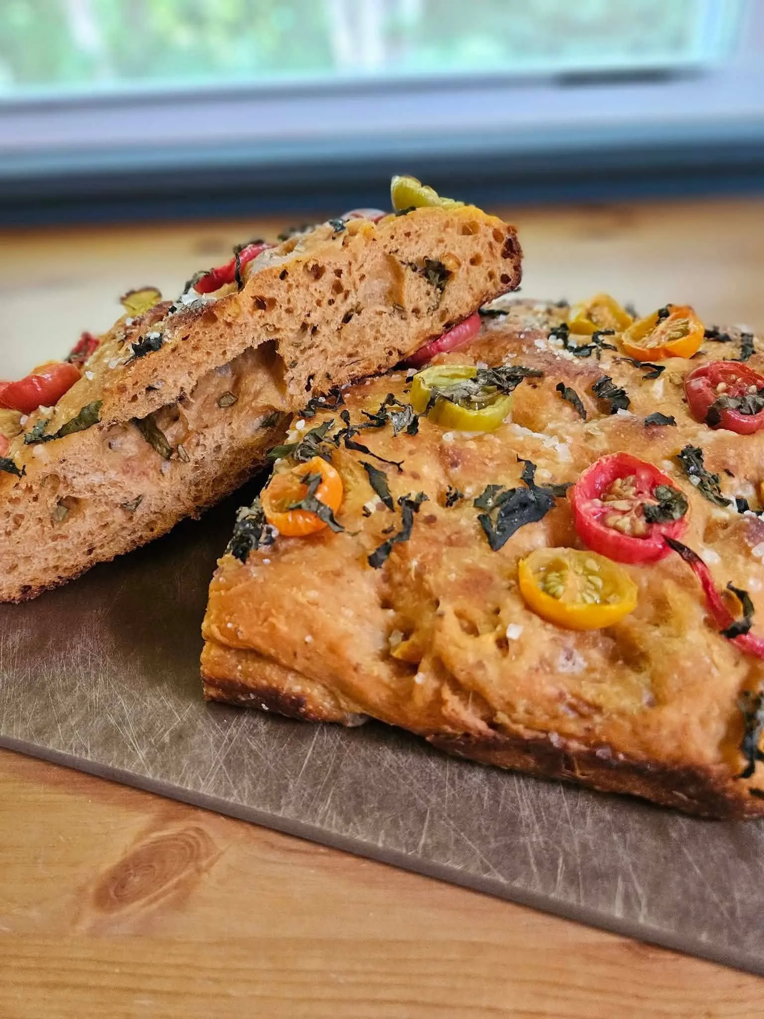 Artisan focaccia with fresh herbs, cherry tomatoes, and peppers